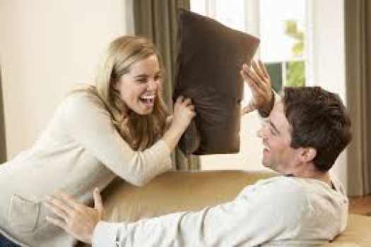 A man and woman are playing with pillows.