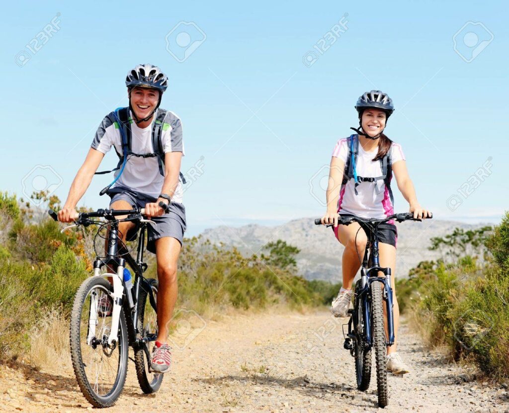 Two people riding bikes on a dirt path.